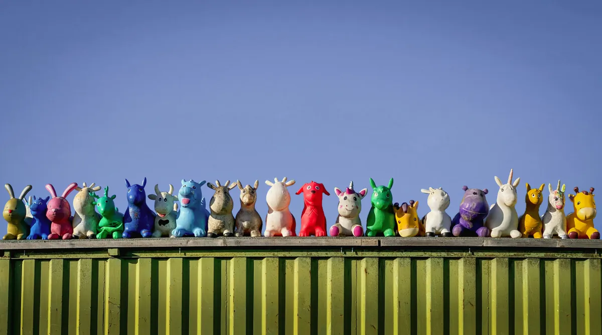 Row of colourful and unique toy animal figures lined up against a blue sky, symbolising the diversity, individuality and joy of parenting children with special needs or neurodiversity
