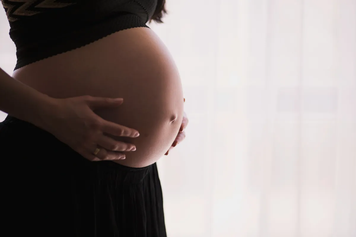 Pregnant woman gently holding her baby bump, symbolising the emotional journey of pregnancy and the importance of mental health support for expectant mothers
